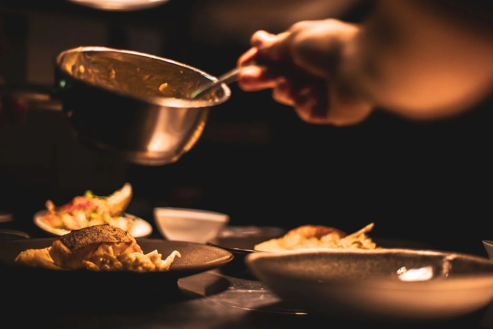 Plat gastronomique dressé par le chef dans une cuisine à la lumière tamisée