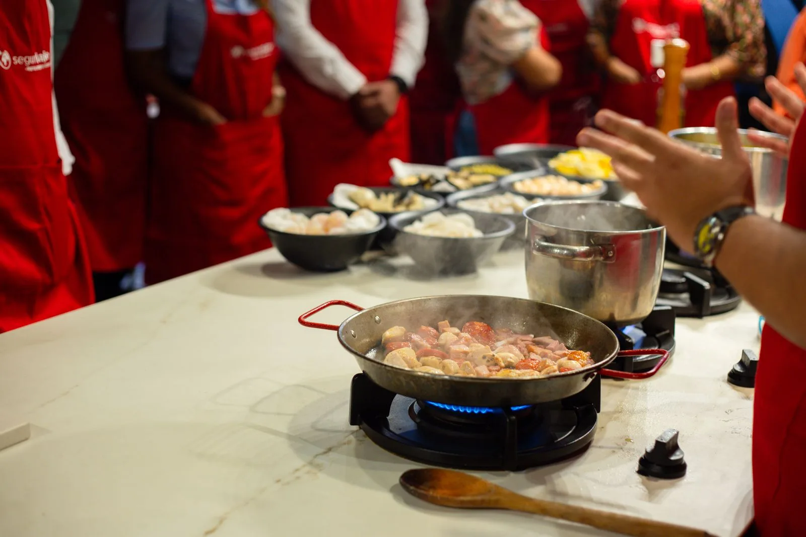 Participants à un atelier de cuisine, mains à la pâte autour du plan de travail