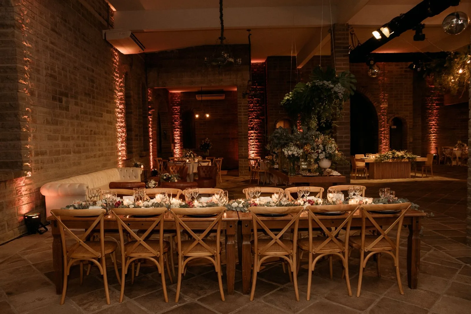 Salle de réception aux grandes tables en bois et compositions florales